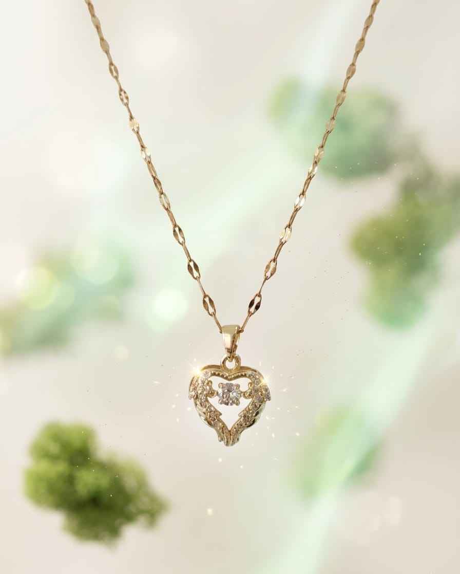 Gold-tone heart pendant necklace with faceted crystal center and ornate sparkle border