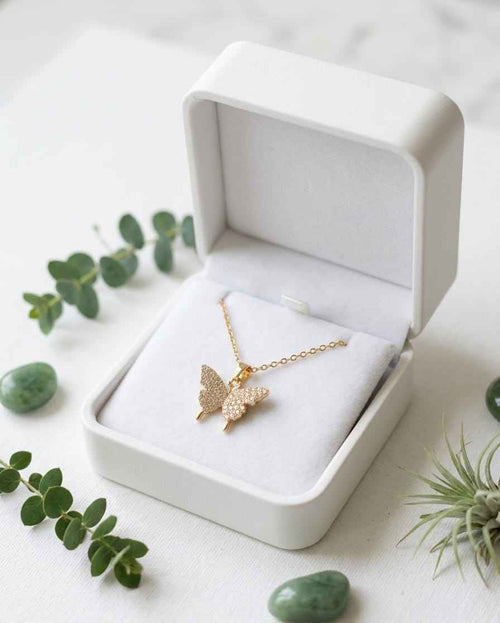 Gold butterfly pavé necklace with chain, shown in a jewelry box