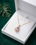 Gold necklace with teardrop amethyst pendant and small halo bezel, shown in gift box
