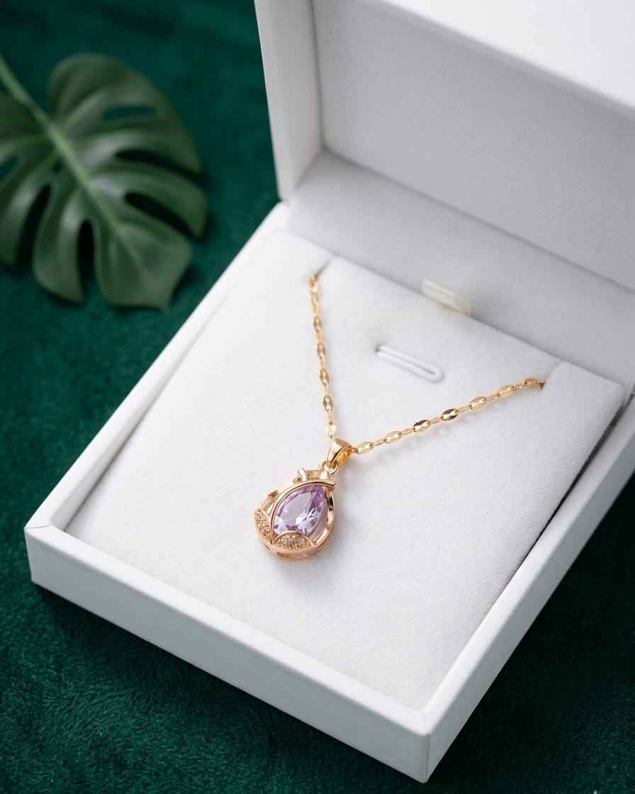 Gold necklace with teardrop amethyst pendant and small halo bezel, shown in gift box