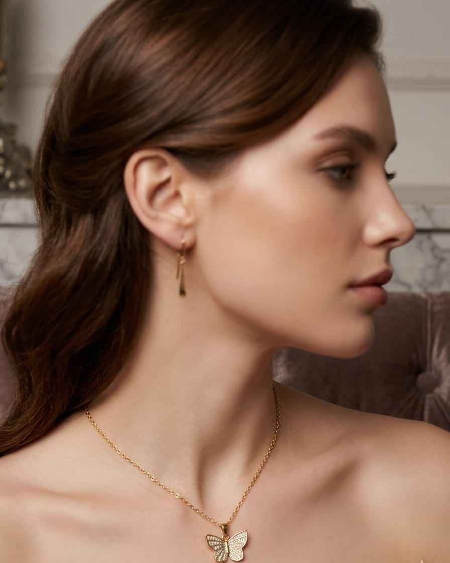 Gold butterfly sparkle necklace worn on model with thin chain