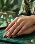 Gold sculpted cuff ring with twisted ridged wave design, worn on a finger