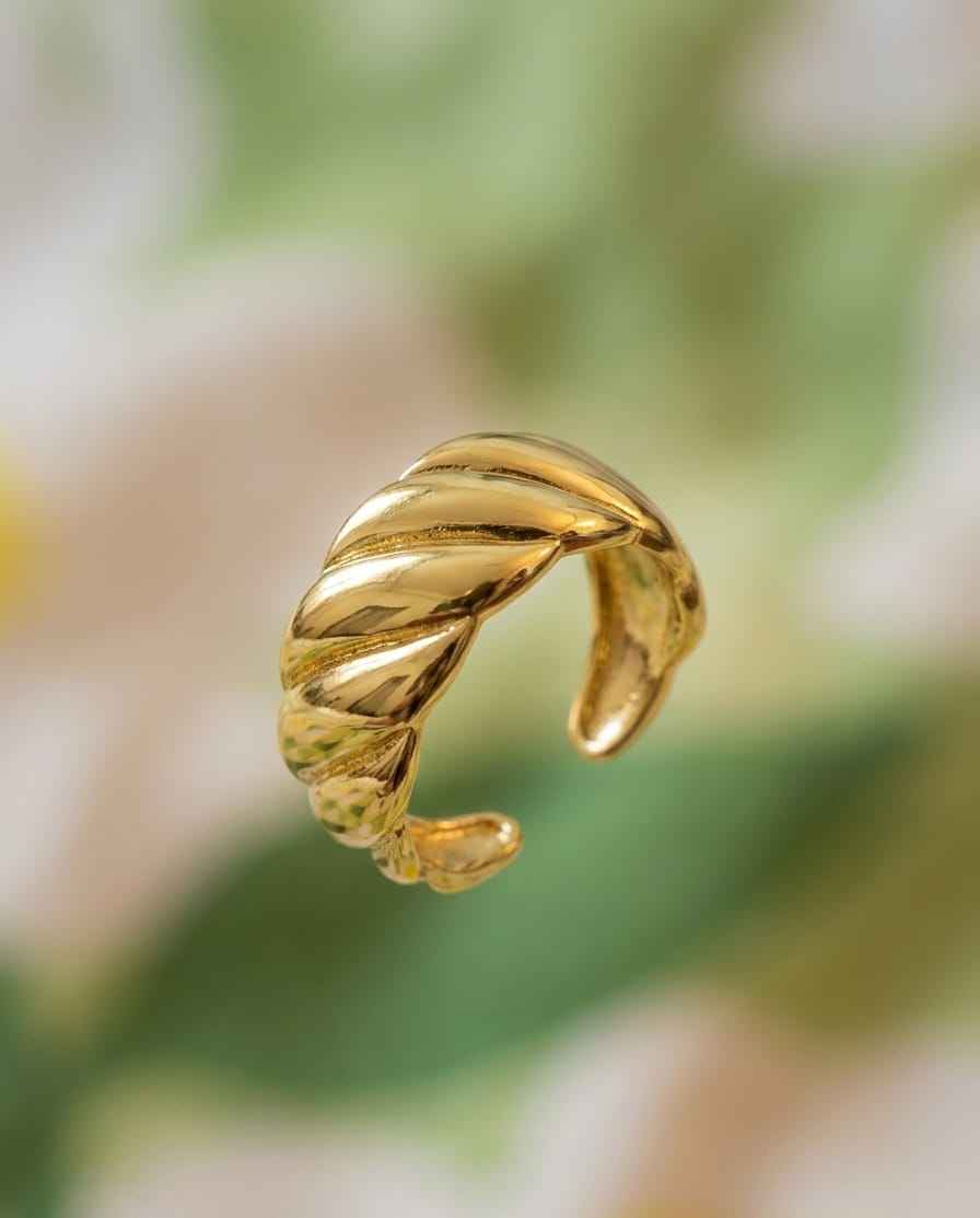Gold sculpted cuff ring close-up with twisted ridged wave band