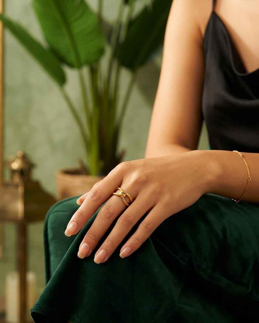 Gold intertwined open ring on finger with angled cross design