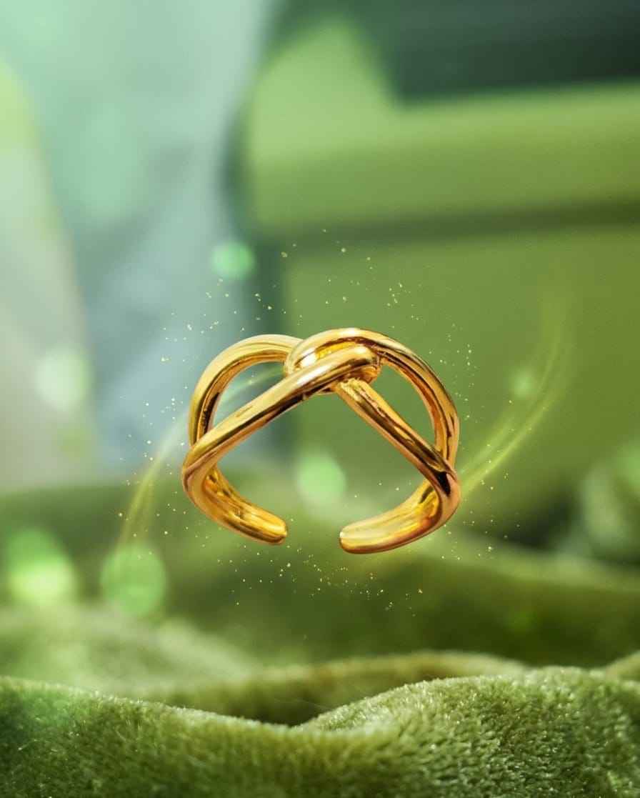 Gold intertwined open ring with angled crisscross bands on green cloth