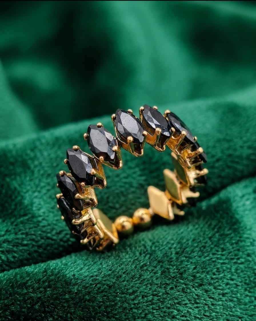 Open ring with dark marquise stones and gold-tone prong setting on soft fabric