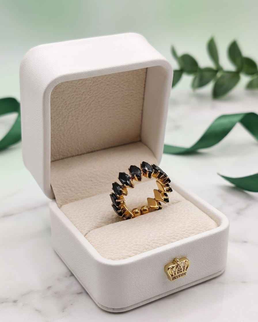 Open marquise gemstone ring with dark stones and gold-tone prong setting in box