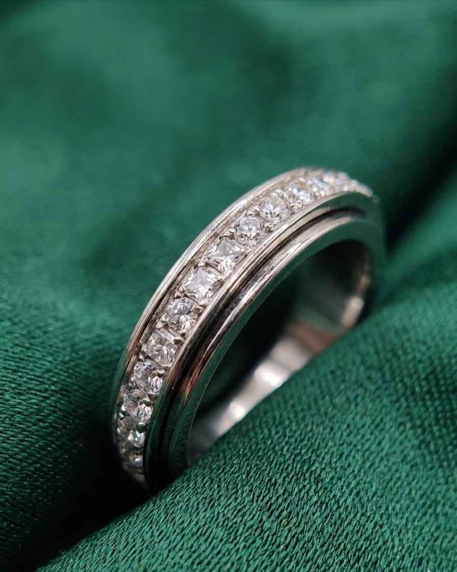Close-up of a silver pavé band ring with clear stones on green fabric