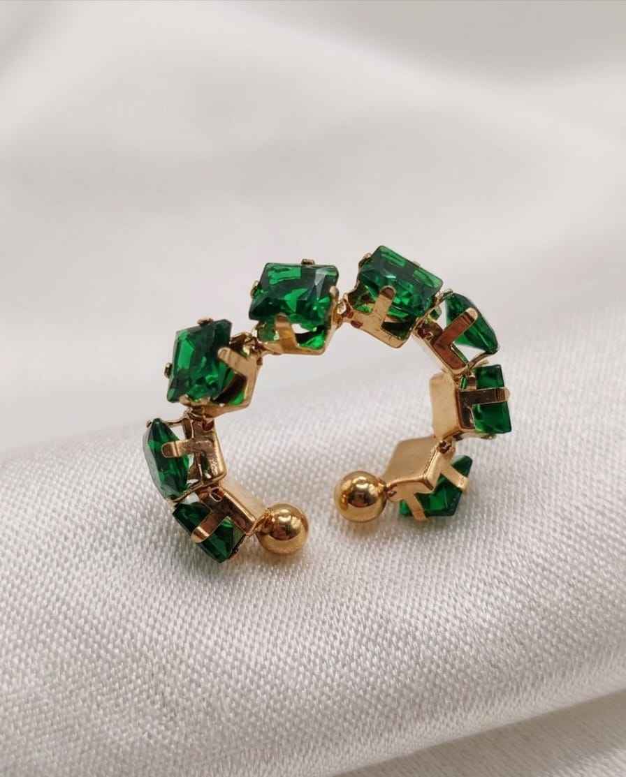 Close-up open band ring with green square stones and gold-tone prong bezels
