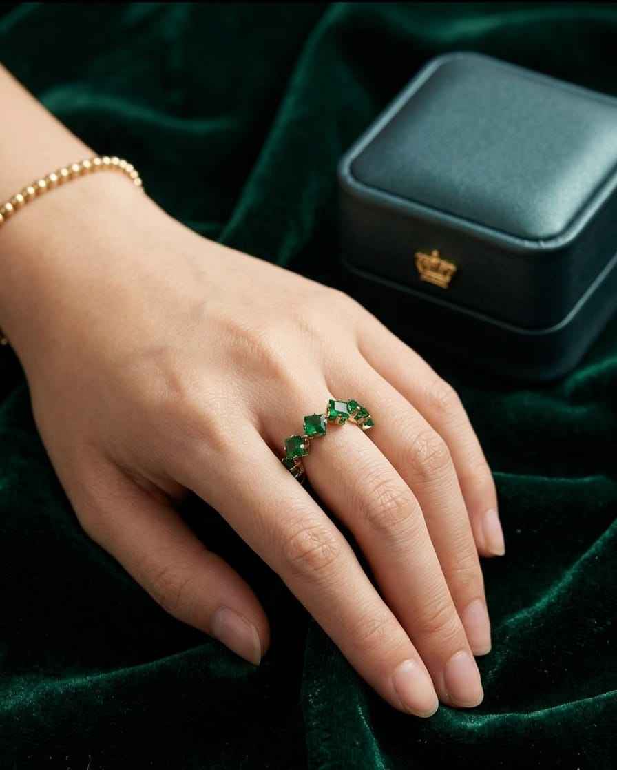 Open band ring on hand with green emerald-cut stones and gold-tone bezels
