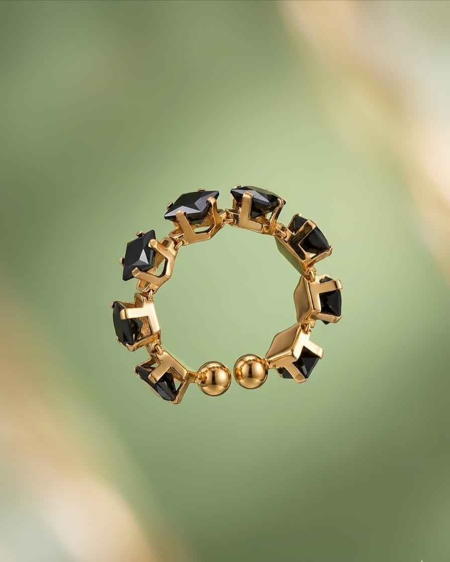 Circular gold-tone ring with dark square gemstones and small round gold accents