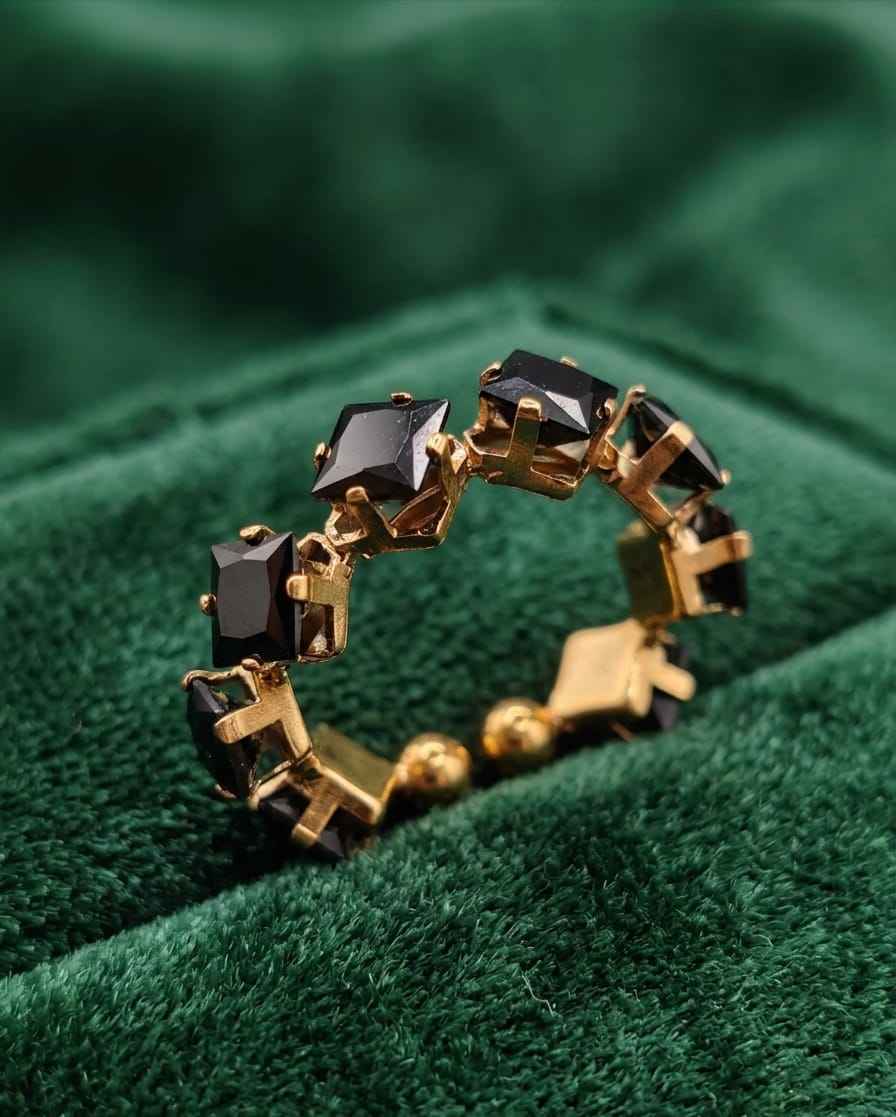 Gold-tone ring with dark square gemstones and round gold bead details