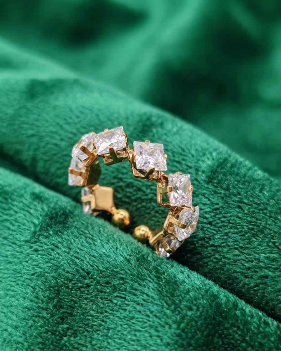 Gold-tone crystal ring with alternating square clear stones on a faceted band