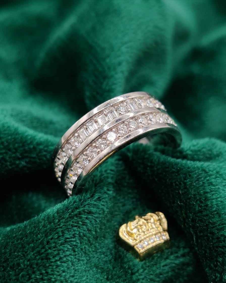 Silver-tone triple band ring with clear stone rows, side view on green velvet