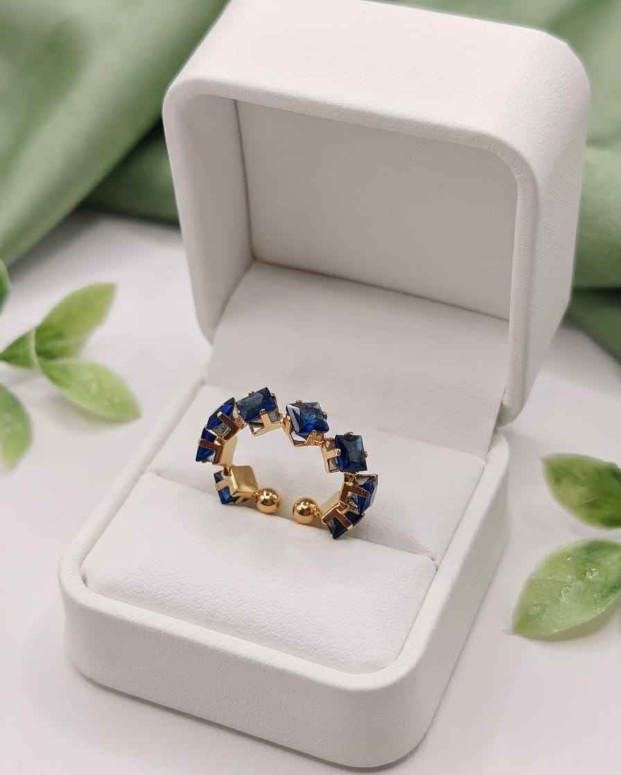 Gold-tone open ring with blue square stones displayed in a jewelry box