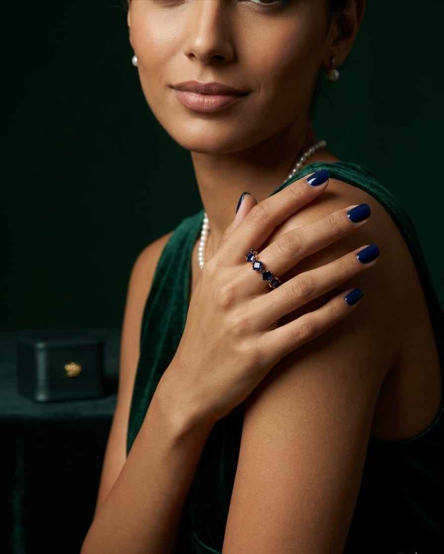 Open ring on finger with blue square stones and gold-tone setting