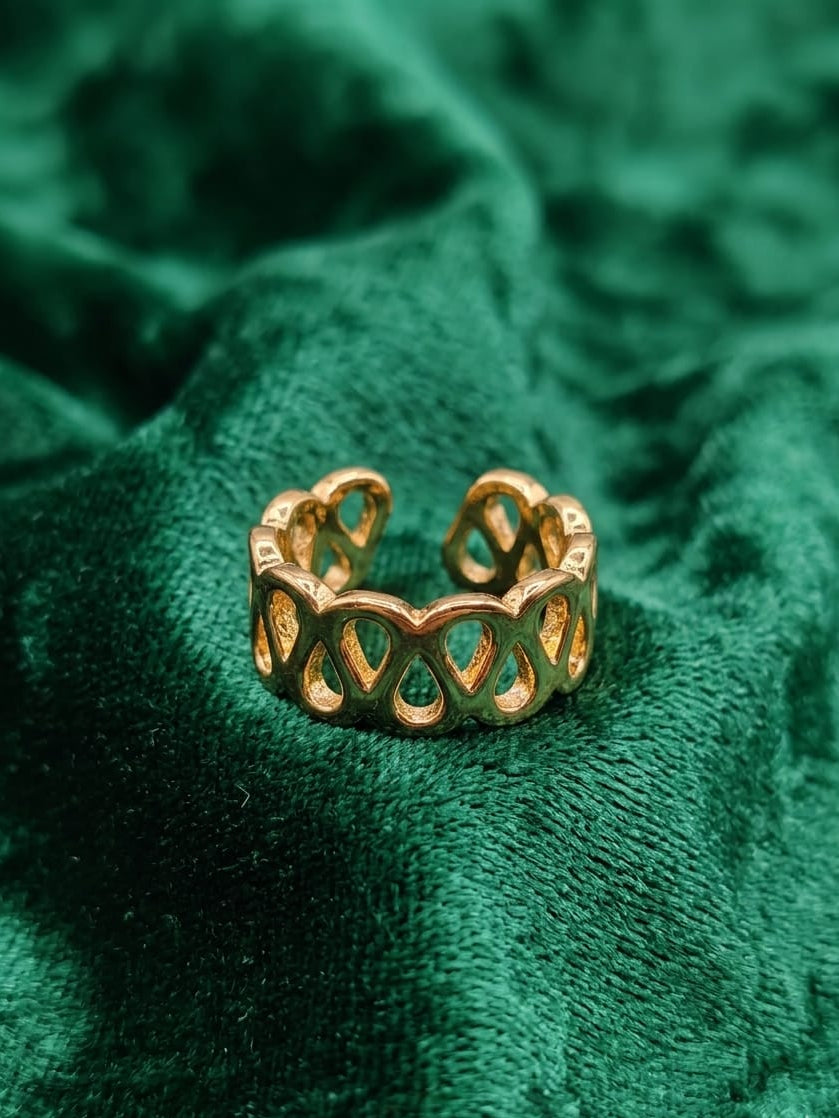 Open loop ring close-up, gold-tone open lattice with green inlays.