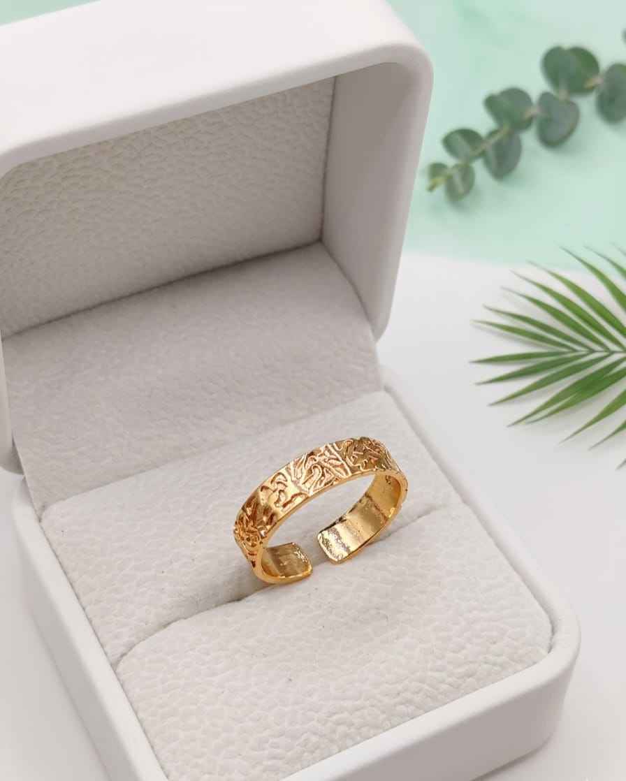 Gold-tone engraved band ring in white gift box, raised pattern visible