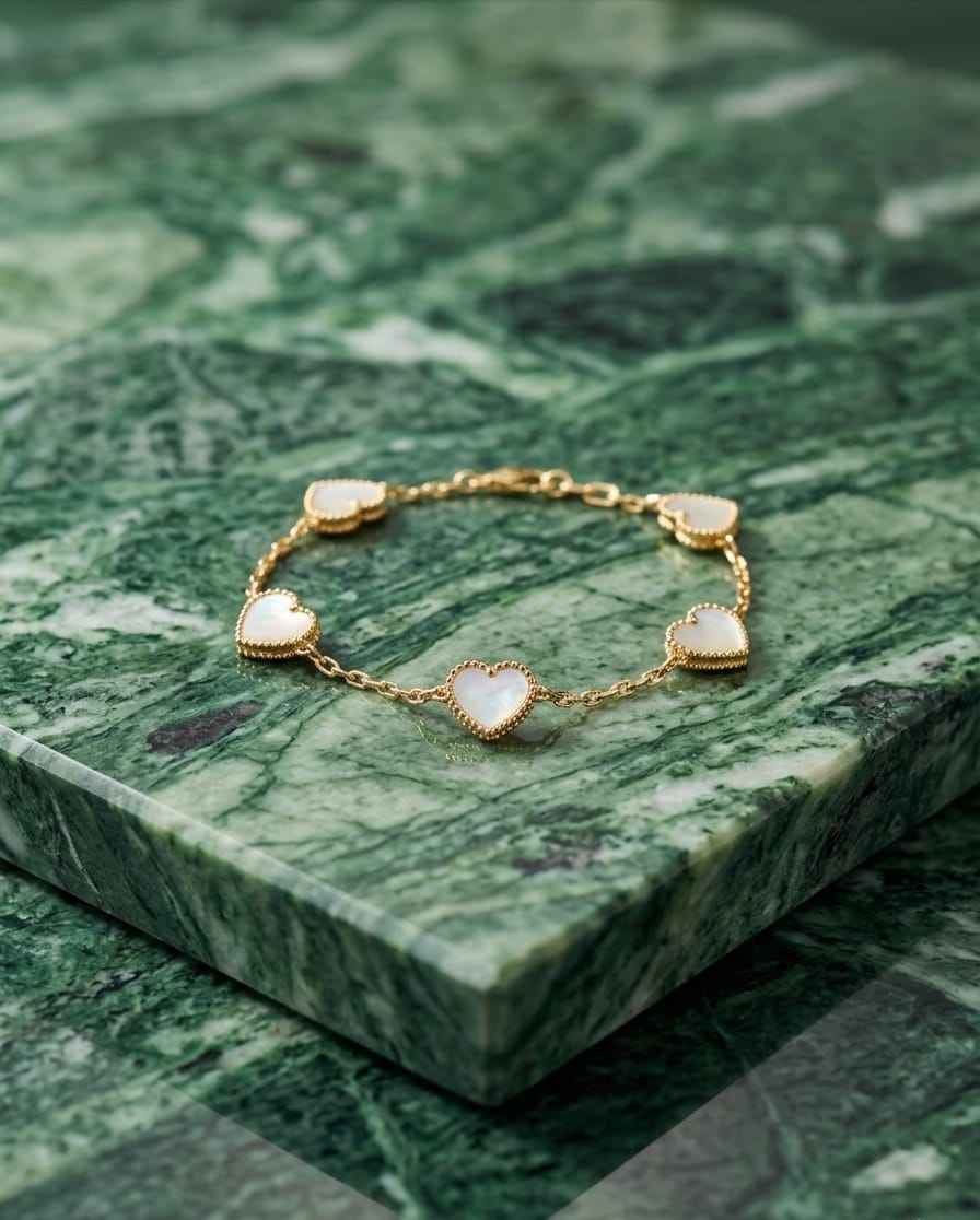Gold bracelet with five white heart charms, scalloped edges