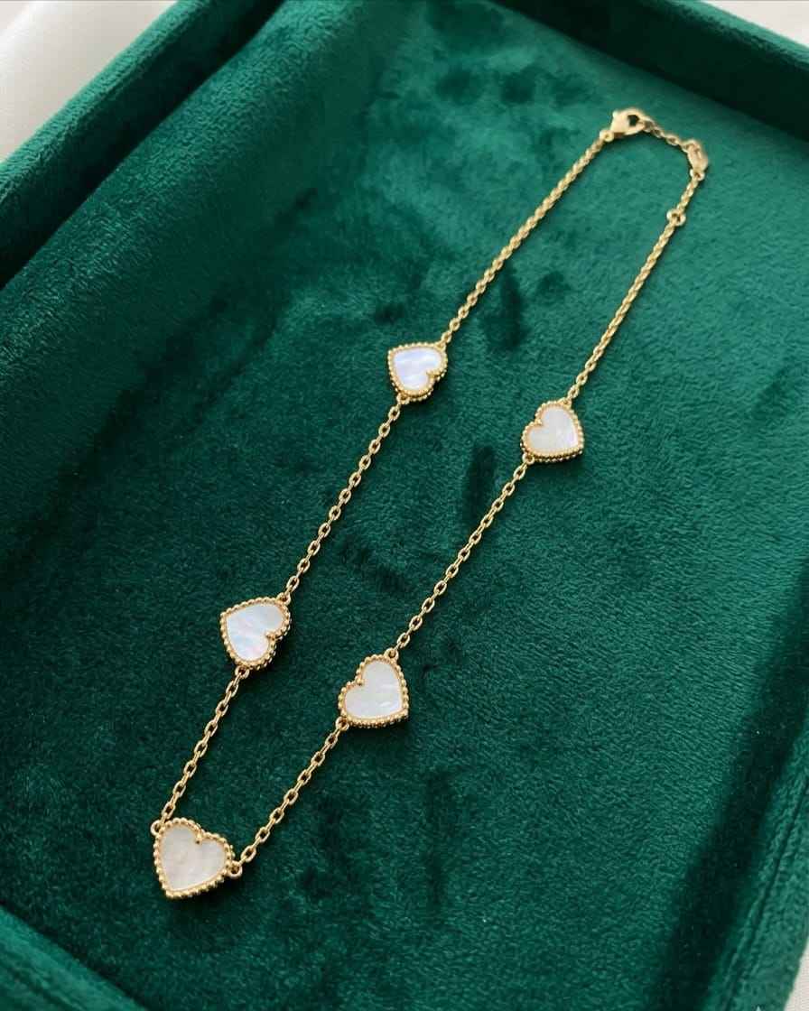Gold heart charm chain with five white enamel hearts