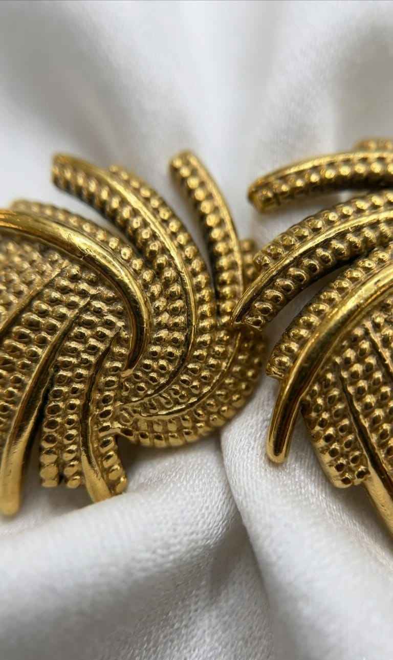 Gold ridged swirl stud earring detail with textured metal finish