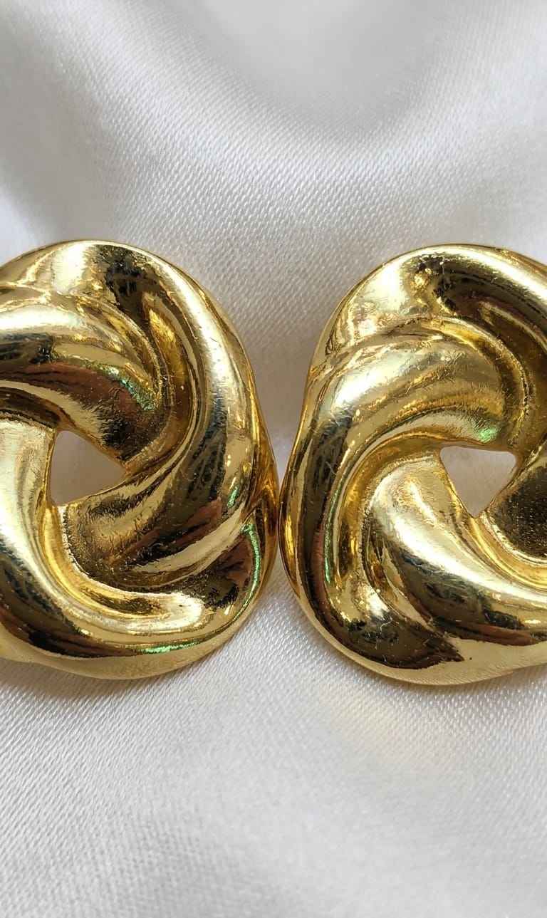 Close-up of gold twisted knot stud earrings with glossy twisted swirl design