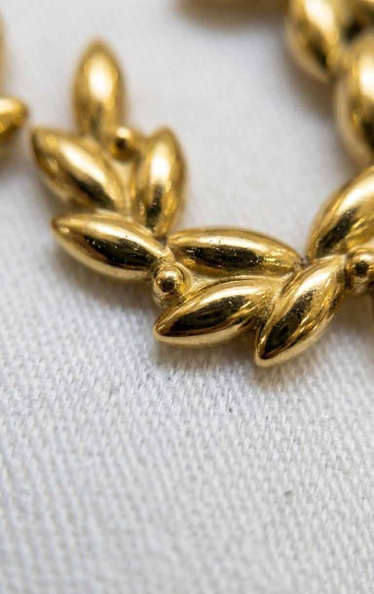 Close-up of gold leaf wreath hoop earrings with leaf-shaped metal links